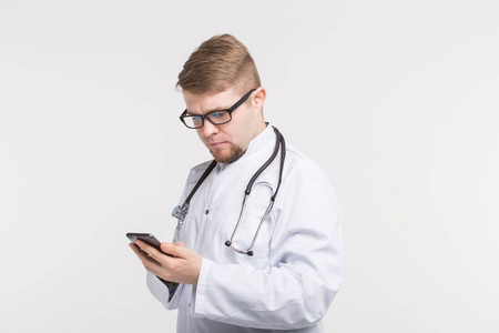 健康和医学医生戴听诊器, 看着手机屏幕上的白色背景