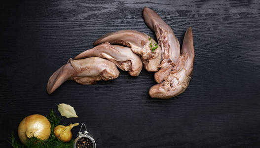 生猪肉或牛肉舌，洋葱湾叶和黑胡椒在黑色木制美食家的食物概念，免费的文字空间