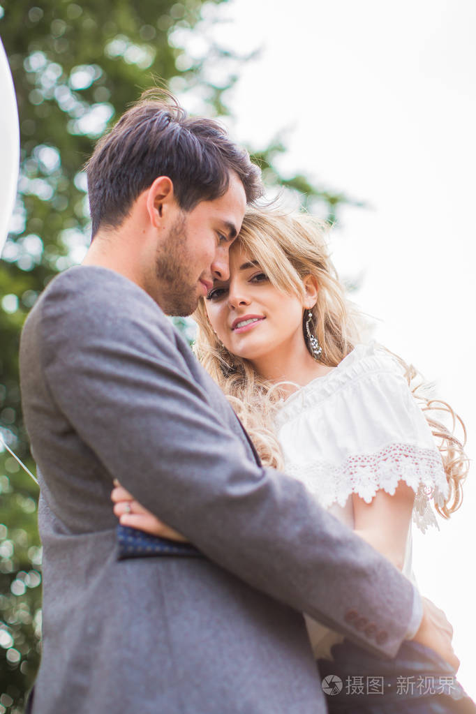 这对年轻幸福浪漫的夫妇站在户外阳光下拥抱