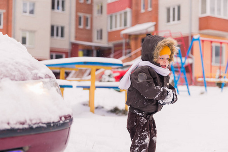 可爱的微笑的小男孩站在院子里玩雪