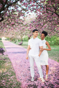这对年轻快乐的浪漫夫妇站在路上，公园里有花瓣