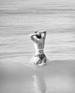 穿着比基尼的漂亮女孩在一个荒芜的海滩上摆姿势。白沙, 绿松石海和一个年轻的女孩