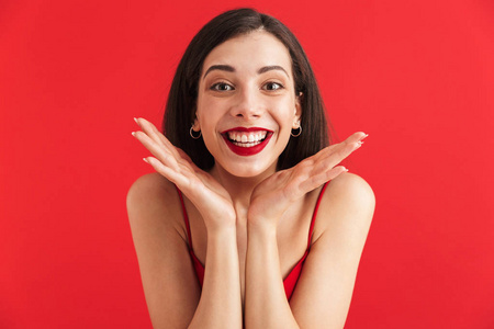 一个兴奋的年轻女子的肖像，穿着红色背景的衣服，双手握在她的脸上
