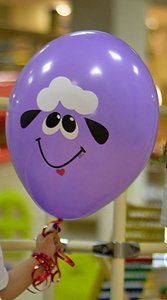 孩子的手拿着气球是紫色的，在生日那天有一只羔羊的照片