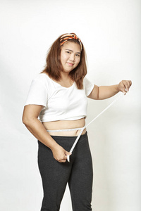 肥胖的年轻女子亚洲人，白色背景的测量磁带工作室。