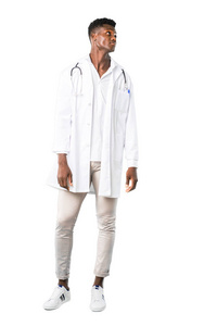 全身的非裔美国医生站着，抬头看着白色背景上严肃的脸
