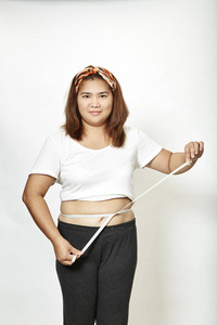 肥胖的年轻女子亚洲人，白色背景的测量磁带工作室。