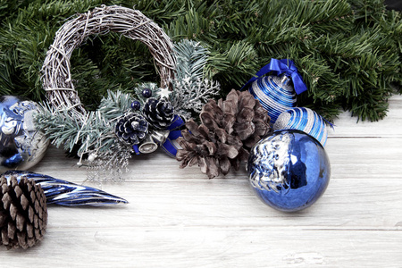 圣诞配件在蓝色圆锥和冷杉枝上的木制白色背面空间设计阳光来自左边。 节日背景的礼品创意