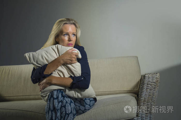 焦虑,痛苦,沮丧,坐在家里的沙发上,悲伤,绝望地抱着枕头,处于中年危机