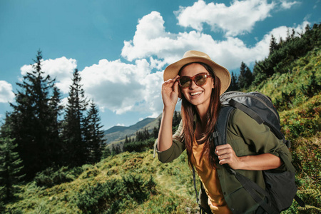 带背包的年轻女性旅行者在绿色草地上摆姿势