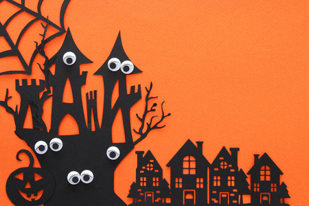 万圣节假期概念。 橙色背景下闹鬼的女巫之家。 俯视图平躺