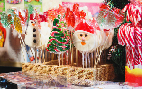 传统糖果的形式，树圣诞老人雪人在摊位上的棍子在集市上。 新年和圣诞节市场装饰概念