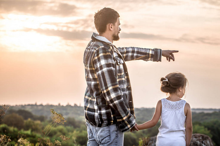 爸爸和女儿在日落时走在大自然中，家庭重视家庭关系