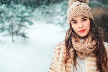 特写冬天的肖像，微笑的年轻女子走在雪地森林里，背景是树