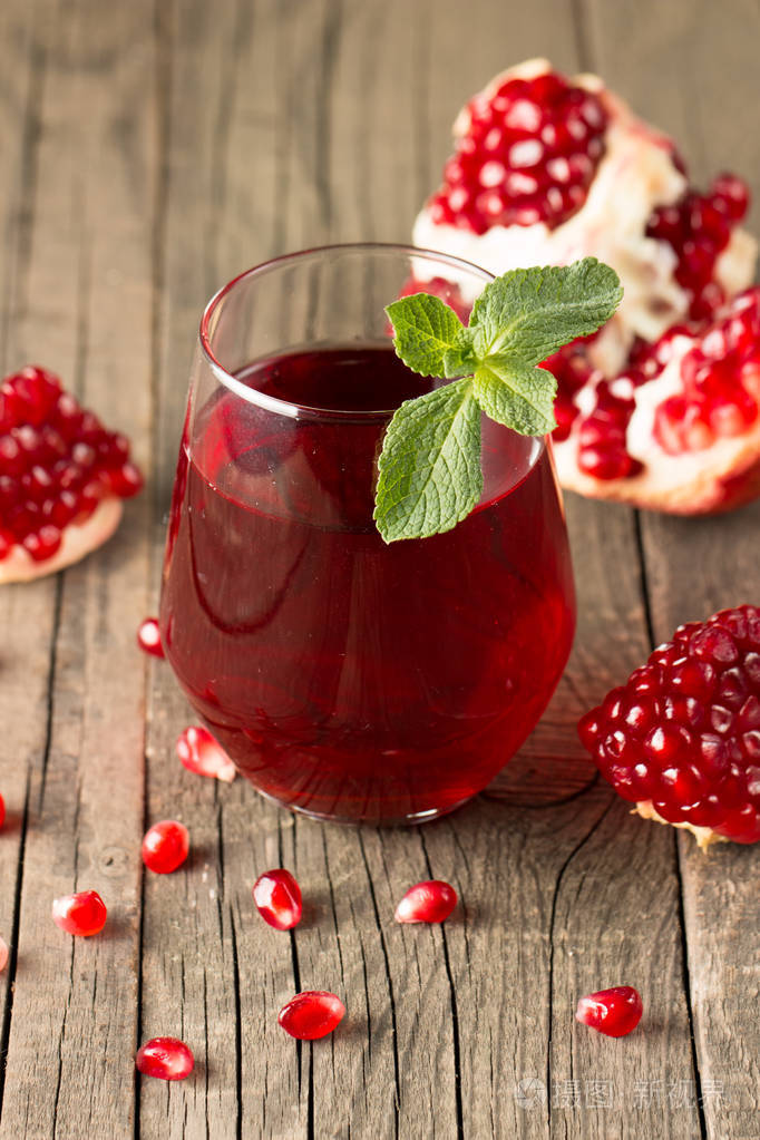 一杯石榴汁木桌上放着新鲜的石榴水果维生素和矿物质健康的饮料概念