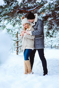冬天的肖像快乐的夫妇在雪林中玩。 男人和女人在户外散步度假