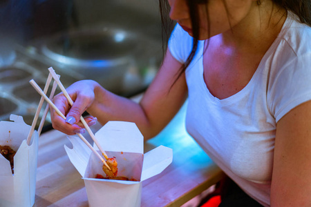 在咖啡馆里用筷子吃亚洲食物的年轻美女特写
