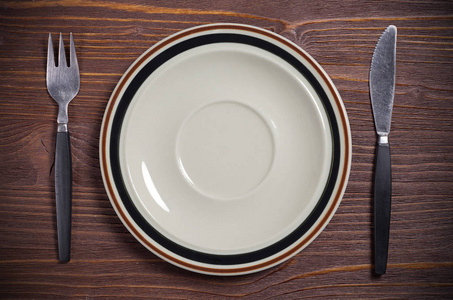 用棕色木桌上的餐具倒空干净的盘子照片