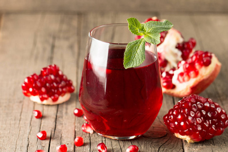 一杯石榴汁,木桌上放着新鲜的石榴水果.维生素和矿物质.