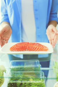 女性站附近打开冰箱充分的健康食品，蔬菜和水果的肖像