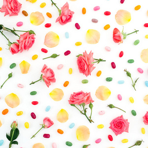 由玫瑰花和花瓣制成的图案，白色背景上有明亮的糖糖。 平躺顶部视图。