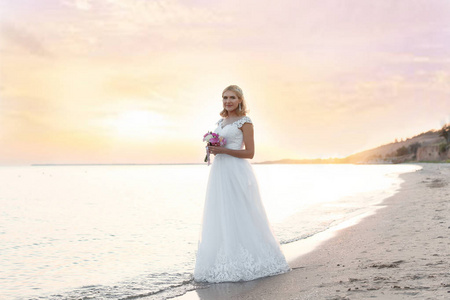 日落时分，新娘在沙滩上捧着结婚花束