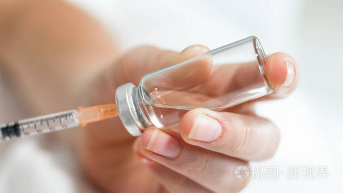 手持小注射器和玻璃安瓿的女性手的宏观图像与药物治疗