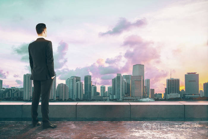 商人在混凝土屋顶上眺望远处,城市景色和阳光. 研究和工作概念