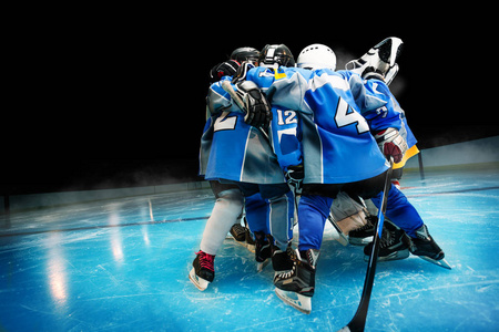 s hockey team standing in circle on ice rink over black backgrou