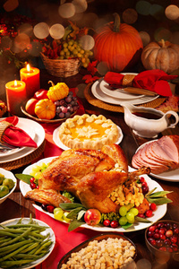 感恩节晚餐。 烤火鸡用蔓越莓装饰在乡村风格的桌子上，配上南瓜蔬菜馅饼鲜花和蜡烛