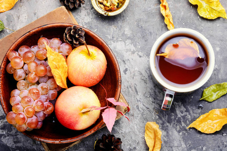 秋天落叶和苹果背景上的茶杯。秋明信片
