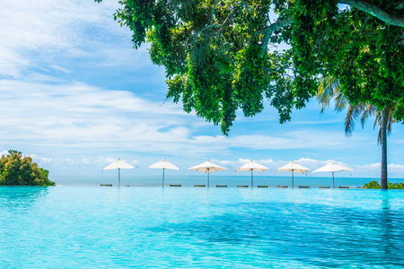 酒店和度假胜地游泳池周围的漂亮豪华雨伞和椅子，供旅行和度假用
