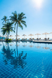 美丽的热带海滩和大海，在酒店度假胜地的游泳池周围有雨伞和椅子，供旅行和度假使用