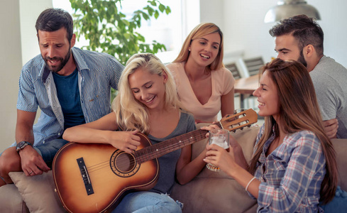 快乐的朋友在家弹吉他和听音乐。