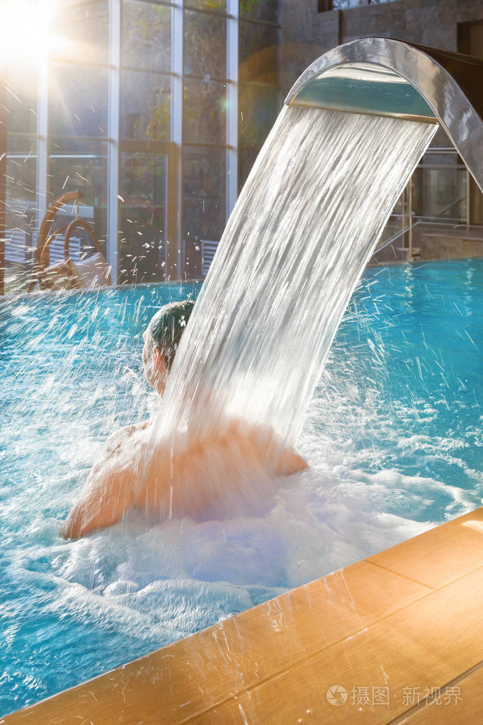 英俊的男人在游泳池放松,淋浴按摩水疗,在豪华酒店与