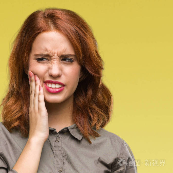 年轻的美女,在孤立的背景下,用手摸嘴,因为牙痛或牙齿上的牙齿疾病