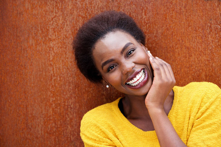 在棕色背景下微笑的年轻黑人妇女的特写肖像