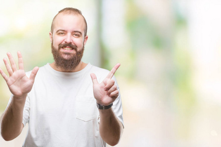 年轻的白种人臀部男子穿着休闲T恤，在孤立的背景上，显示和指向7号手指，同时微笑自信和快乐。
