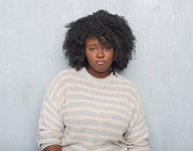 年轻的非裔美国人，加上身材魁梧的女人，穿着一件毛衣，沮丧而担心痛苦，愤怒而害怕。 悲伤的表情。