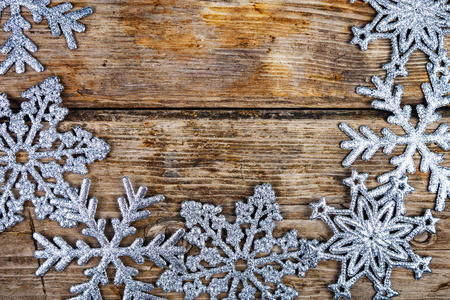 银色的雪花在一个古老的棕色木制背景上。 圣诞装饰。