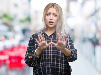 年轻的金发女人在孤立的背景下害怕和恐惧，表情停止手势，双手震惊地喊叫。 恐慌的概念。