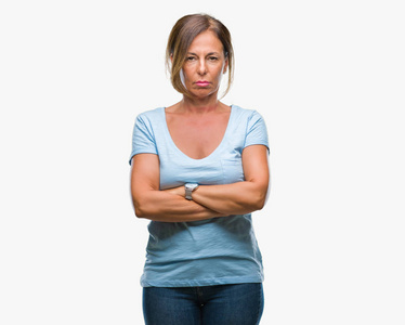 中年老年西班牙裔妇女超越孤立的背景怀疑和紧张的不赞成的表情在脸上交叉的手臂。 消极的人。