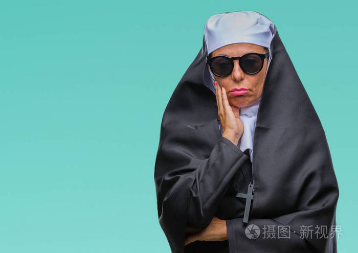 中年资深天主教修女,戴着太阳镜,在孤立的背景下思考,看起来疲惫,厌倦