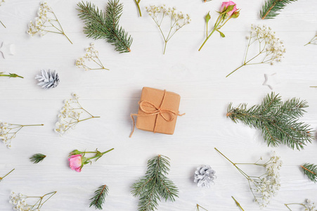 抽象的圣诞节背景与礼物在中心和圣诞元素锥体, 树枝, 玫瑰在白色木质背景上的装饰