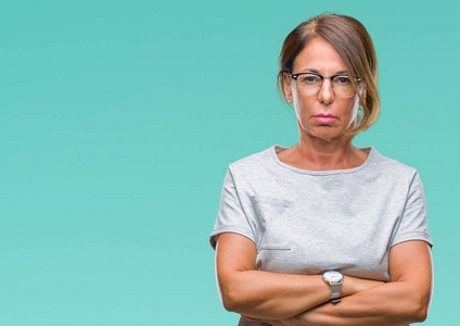 中年老年西班牙裔妇女戴着眼镜，戴着孤立的背景怀疑论者和紧张的不赞成表情的脸上交叉的手臂。 消极的人。