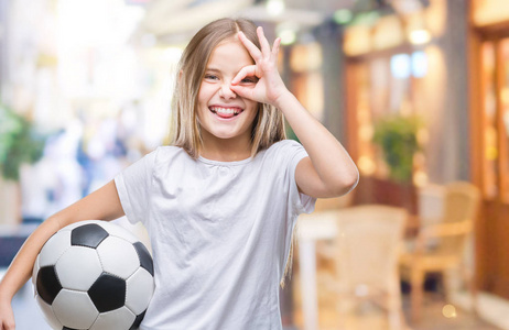 年轻漂亮的女孩拿着足球球在孤立的背景上，快乐的脸，微笑着，做着好的标志，用手盯着手指看