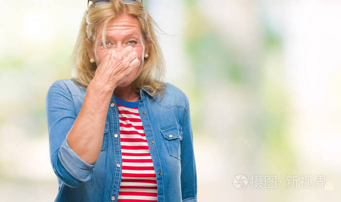 中年金发女人在孤立的背景上闻到一些臭味和令人恶心的难以忍受的气味