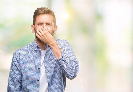 年轻的英俊男子穿着白色t恤,在孤立的背景上闻到了一些臭味和令人恶心