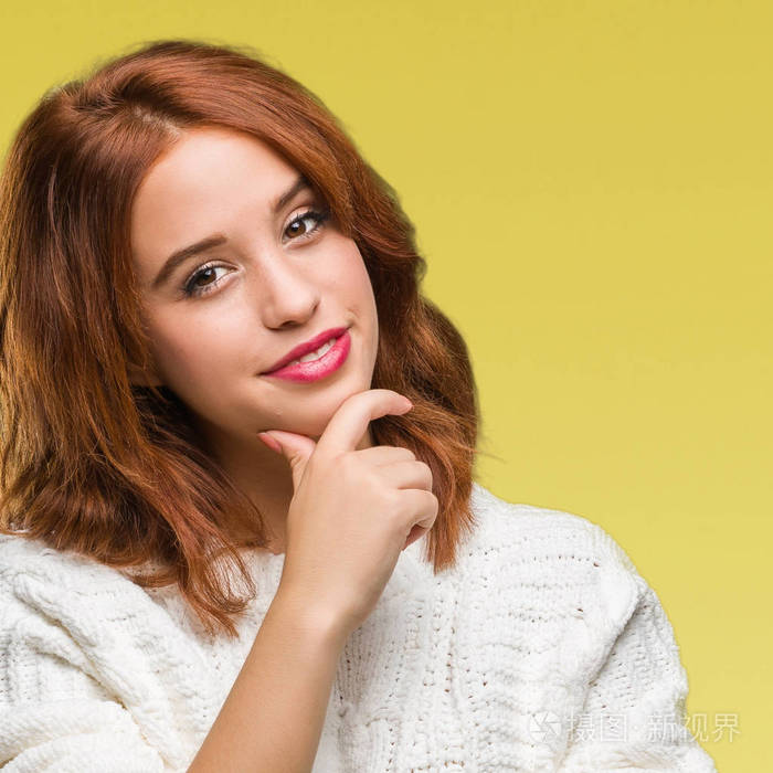 年轻漂亮的女人在孤立的背景上穿着冬天的毛衣,自信地看着相机,微笑着