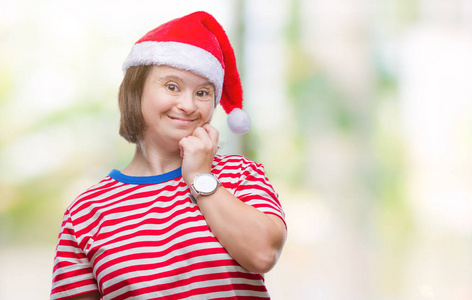 年轻的成年妇女患有唐氏综合症，戴着圣诞帽，戴着孤立的背景，看上去压力很大，紧张，双手咬着嘴的指甲。 焦虑问题。